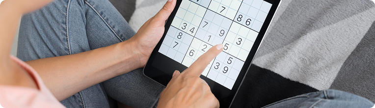Person holding tablet with Sudoku puzzle